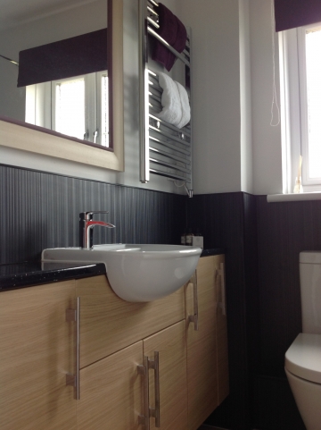 Bathroom with bath, toilet, electric shower and vanity unit with sink, heated towel rail.